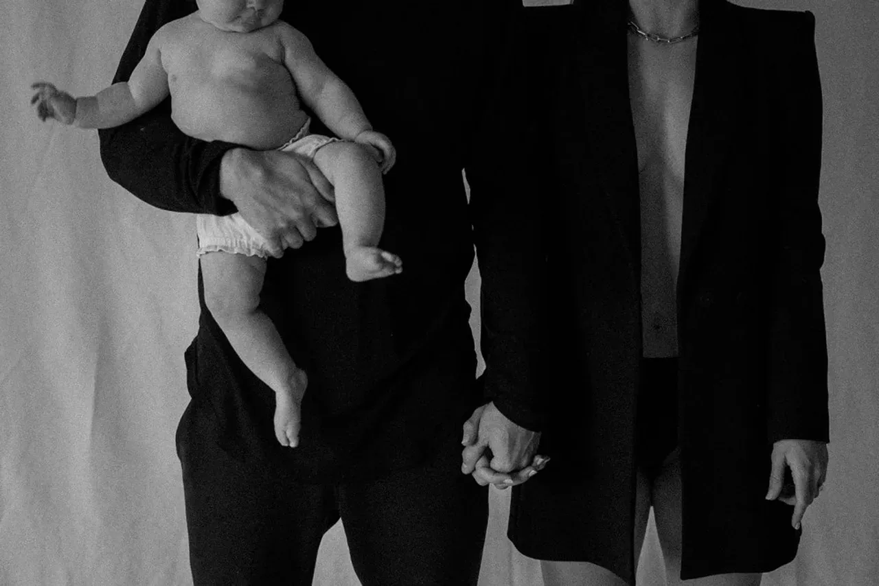 Couple holding hands and an infant.